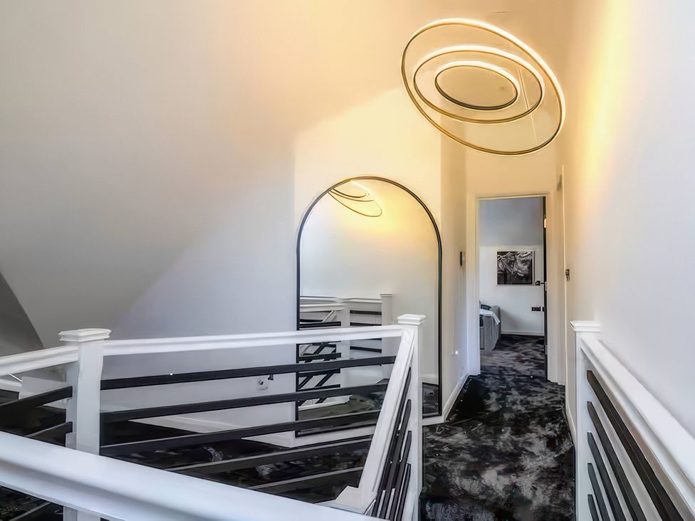A hallway with a mirror and light fixture at 19 Hillside Road, Northwood, Hertfordshire