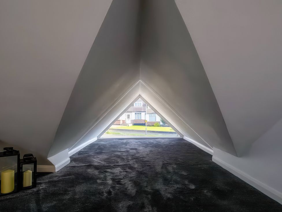 An attic space with a triangular window view at 19 Hillside Road, Northwood, Hertfordshire