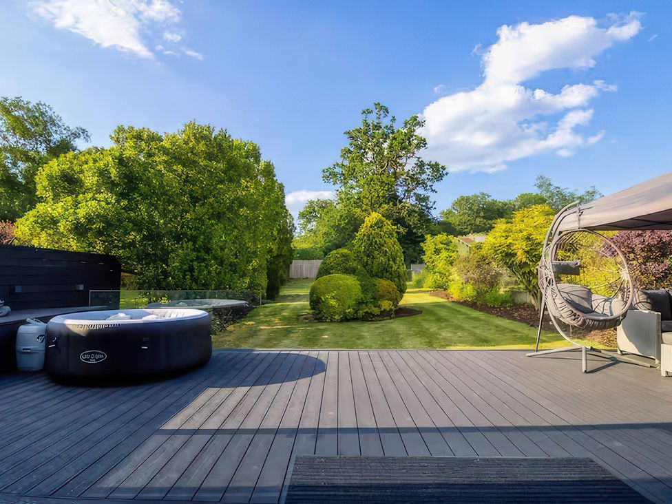 A garden with a hot tub and a hanging chair at 19 Hillside Road in Northwood, Hertfordshire