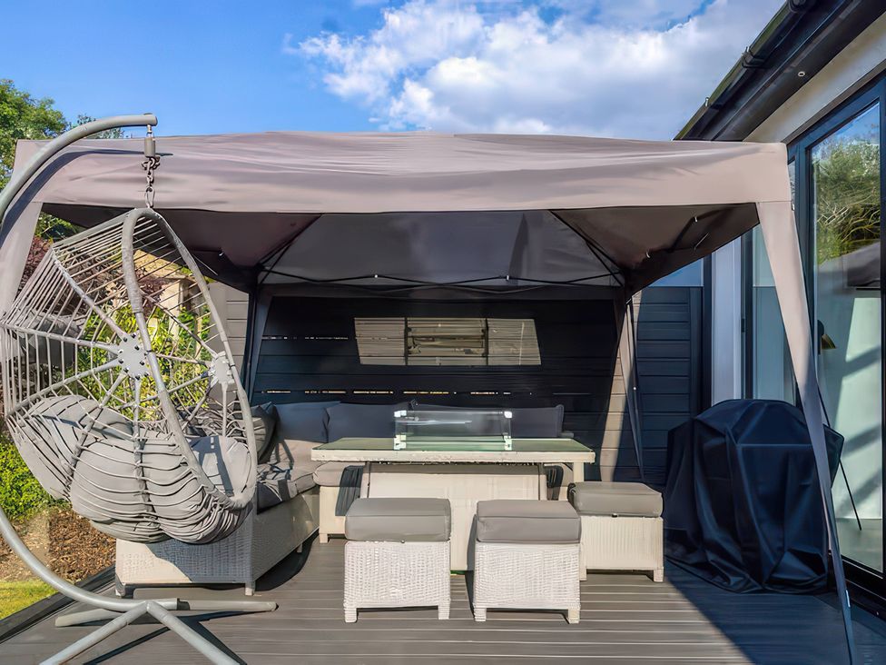 An outdoor seating area with a canopy, table, and hanging chair at 19 Hillside Road, Northwood, Hertfordshire