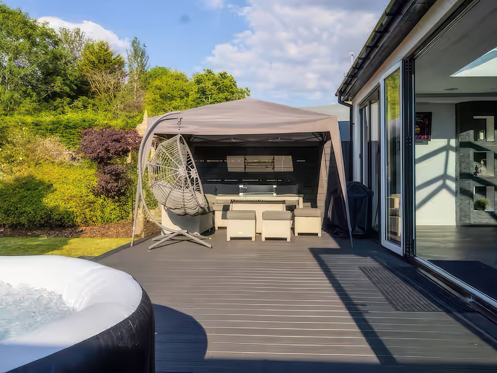 A patio with outdoor seating and a hot tub at 19 Hillside Road, Northwood, Hertfordshire