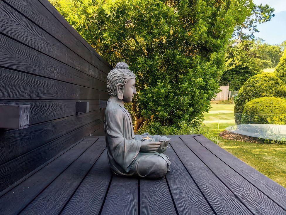 A buddha statue on a wooden deck in a garden at 19 Hillside Road Northwood, Hertfordshire