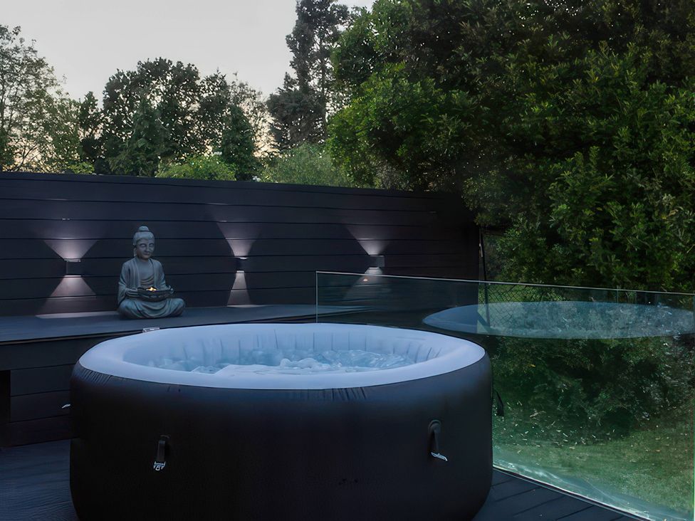An outdoor area with a hot tub and a buddha statue at 19 Hillside Road in Northwood, Hertfordshire