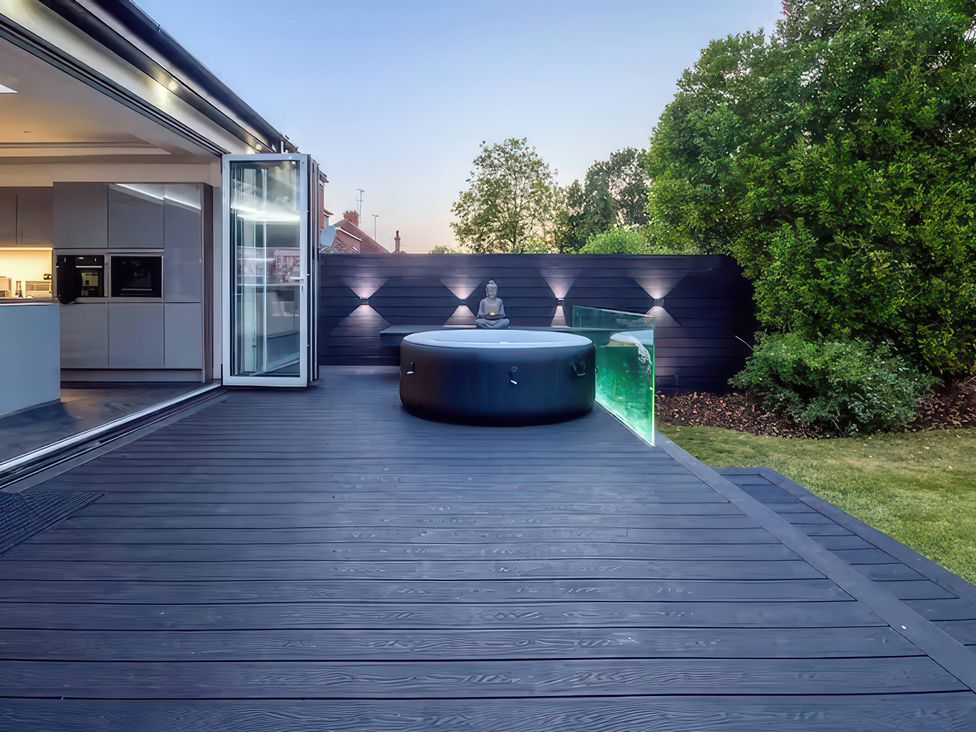An outdoor space with a hot tub, decking, and a buddha statue at 19 Hillside Road Northwood, Hertfordshire