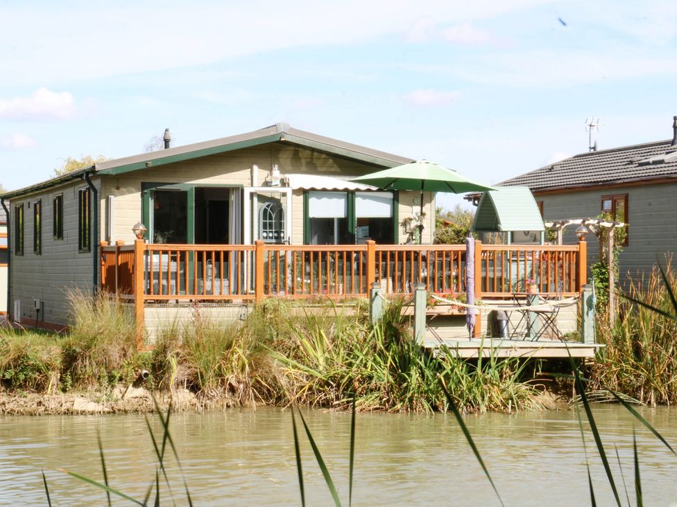 A cabin with a deck and chairs at Patos y Nosotros in Grantham