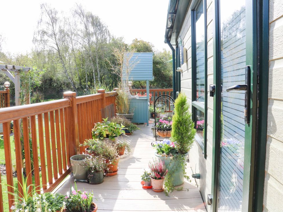 A garden with decking and potted plants at Patos y Nosotros in Grantham