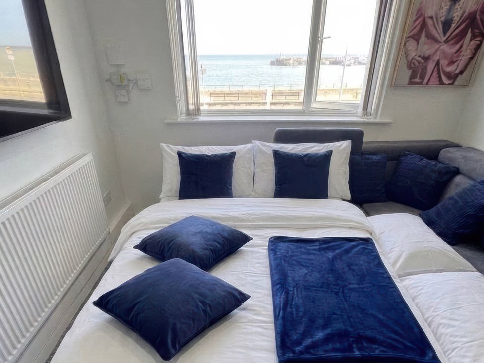 A bedroom with a bed and window overlooking the sea at Flat 3 Brown Lodge Sheerness