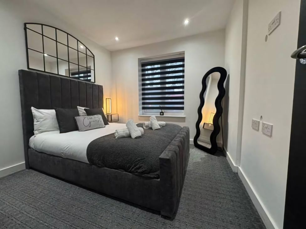 A bedroom with a bed and a mirror at Flat 1 Hilltop Court in Uxbridge