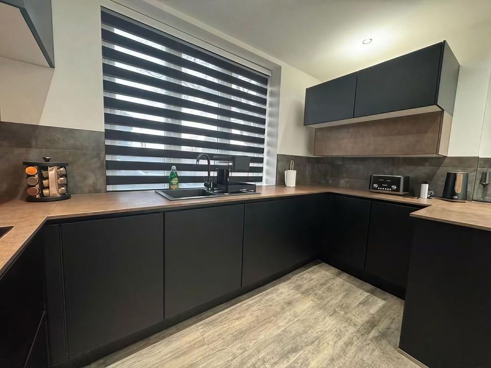 A kitchen with a sink and black cabinets at Flat 1 Hilltop Court Uxbridge