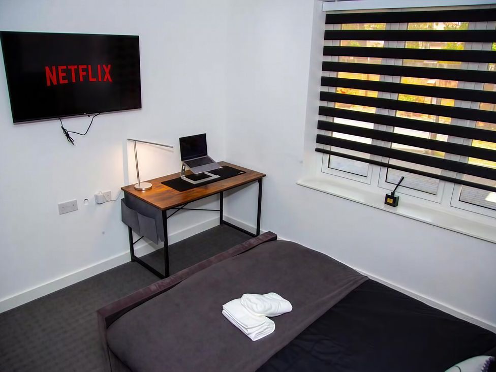 A bedroom with a desk and a TV displaying Netflix at Flat 1 Hilltop Court in Uxbridge