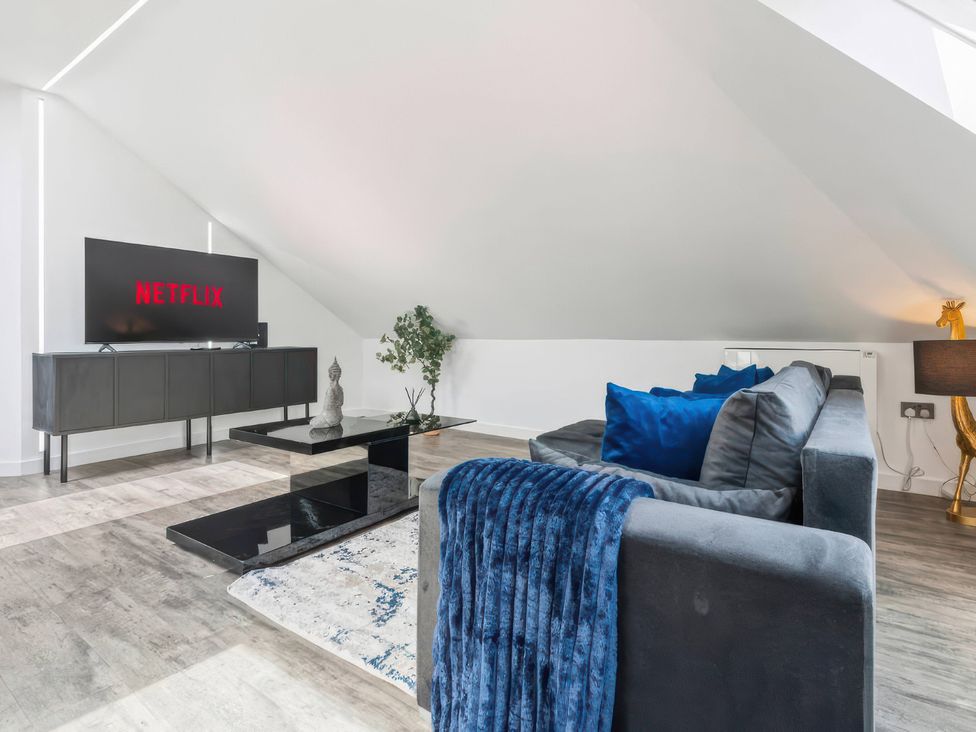 A living room with a television on a stand, couch, and coffee table at Flat 6, Hilltop Court, Uxbridge