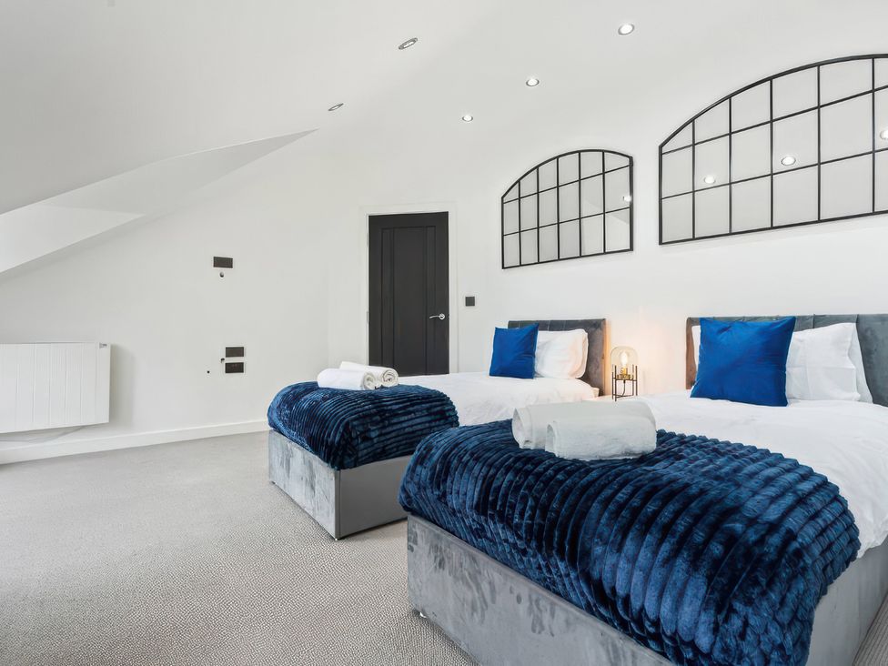 A bedroom with two beds and a door at Flat 6, Hilltop Court in Uxbridge