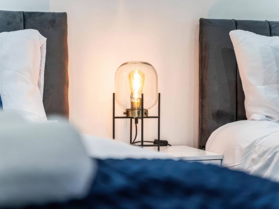 A bedroom with beds and a lamp at Flat 6, Hilltop Court in Uxbridge