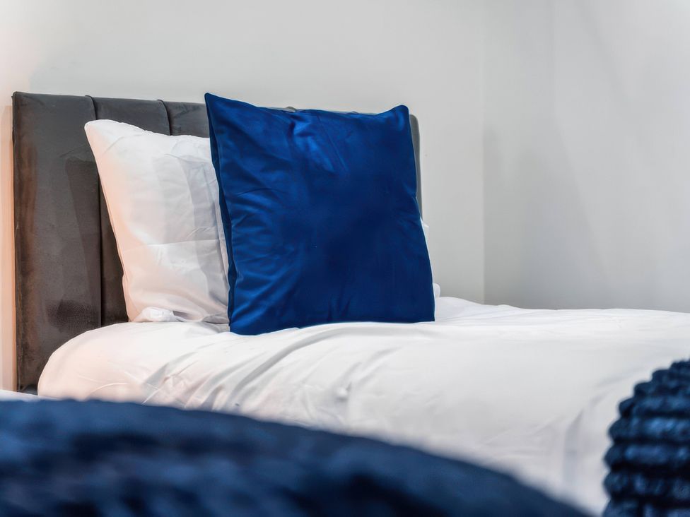 A bed with a blue pillow at Flat 6, Hilltop Court in Uxbridge
