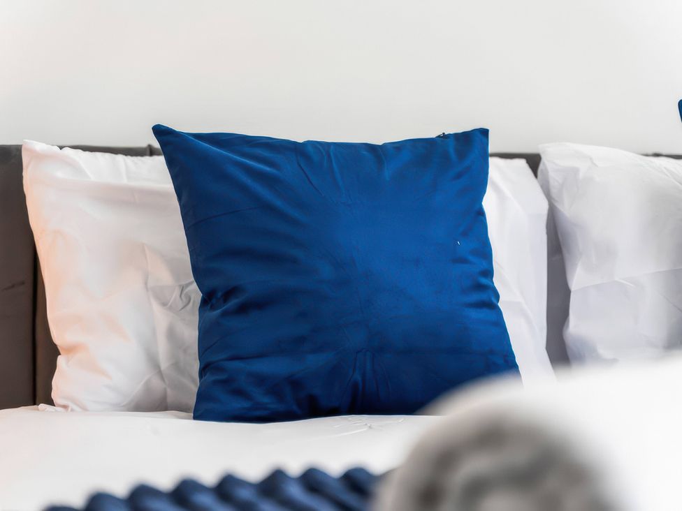 A blue pillow on white bed sheets at Flat 6, Hilltop Court in Uxbridge