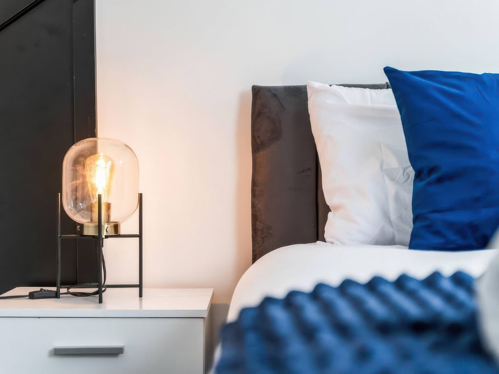 A bedroom with a lamp on a bedside table at Flat 6, Hilltop Court in Uxbridge