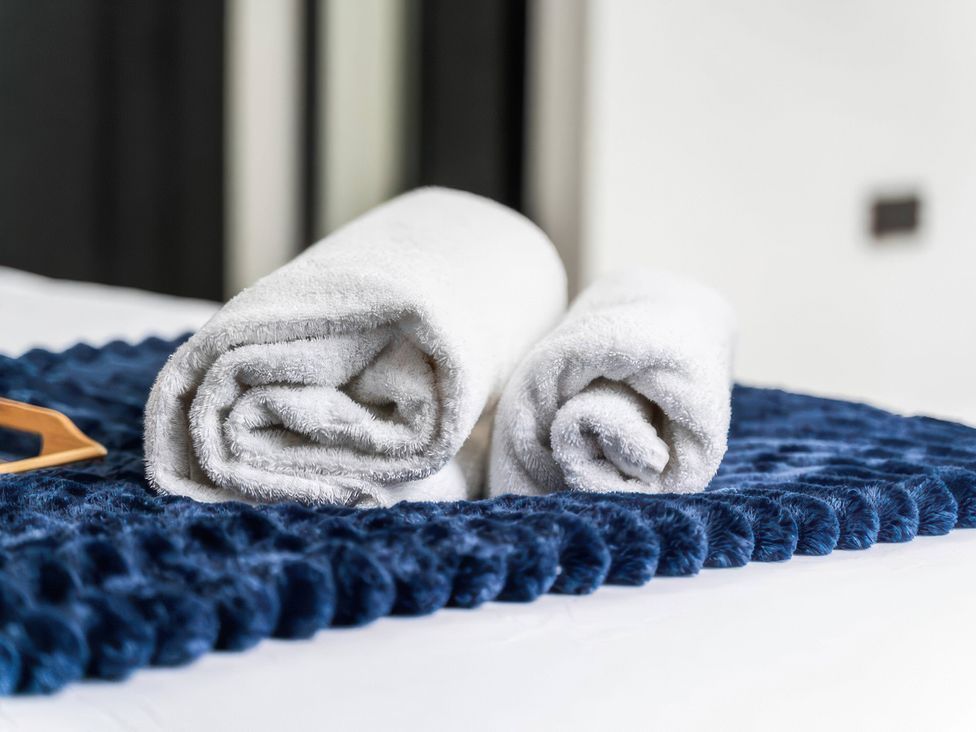 A bed with rolled towels on a blue bedspread at Flat 6, Hilltop Court in Uxbridge