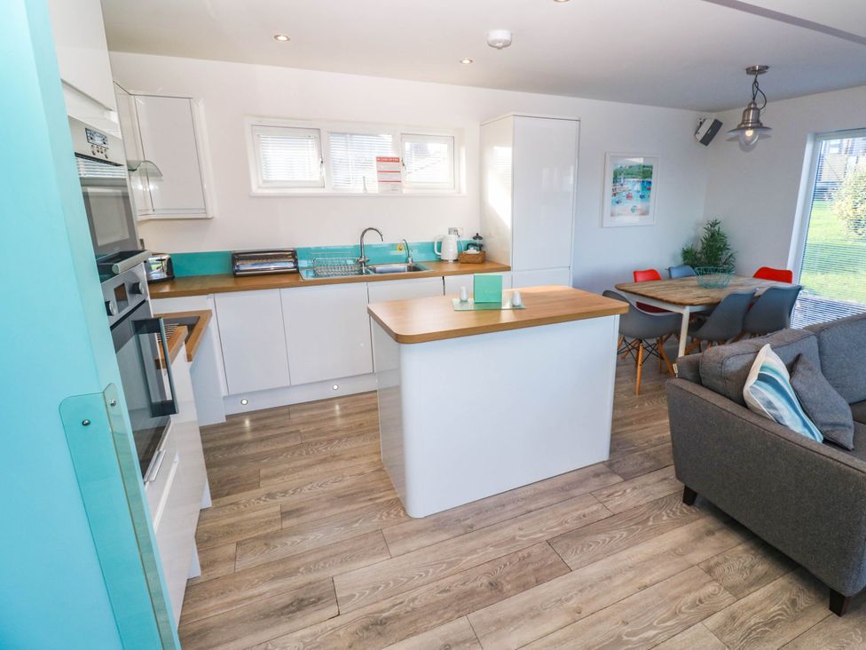 A kitchen with appliances and a dining table at 74 Porthmeor in Redruth
