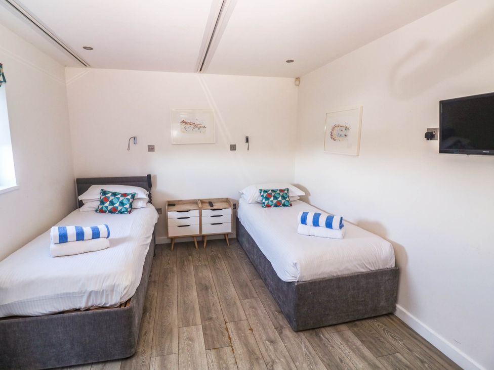 A bedroom with two beds and a television at 74 Porthmeor in Redruth