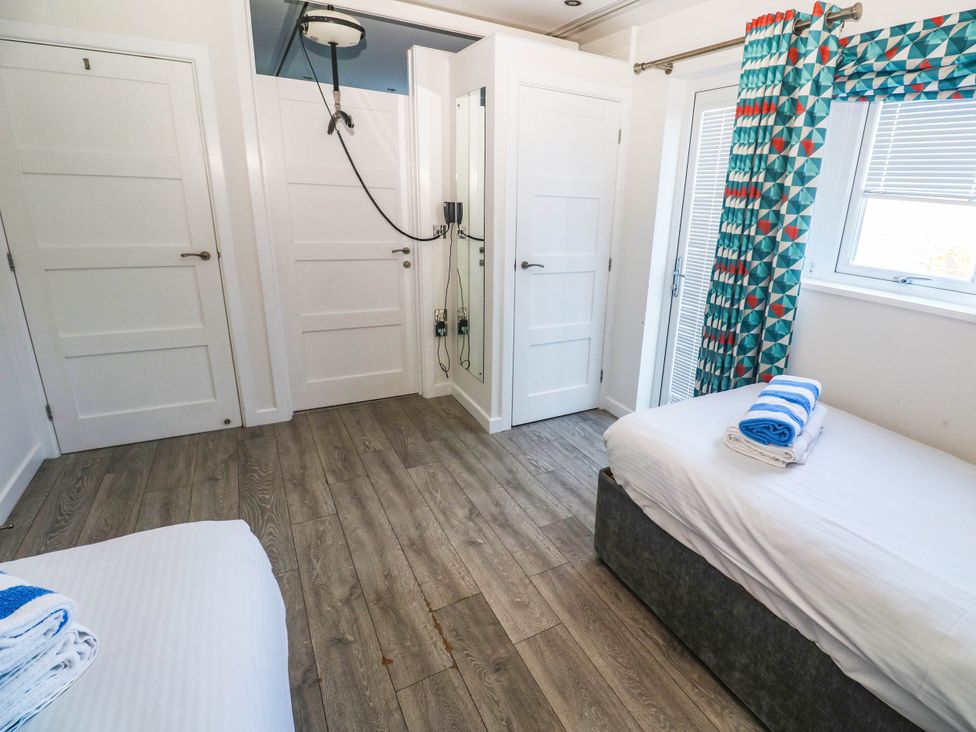 A bedroom with two beds and a shower unit at 74 Porthmeor in Redruth