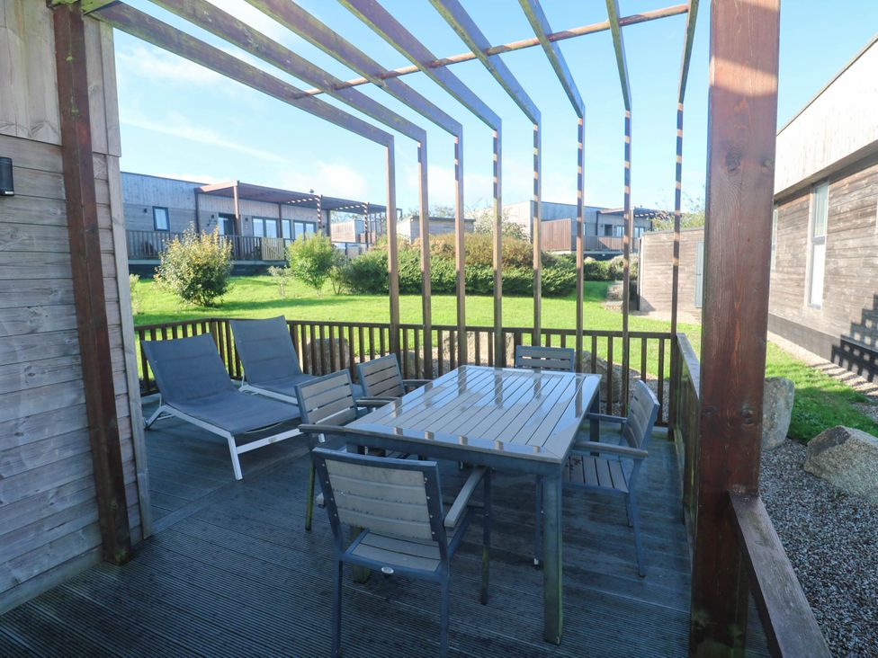 A garden with a wooden deck, table and chairs at 74 Porthmeor in Redruth