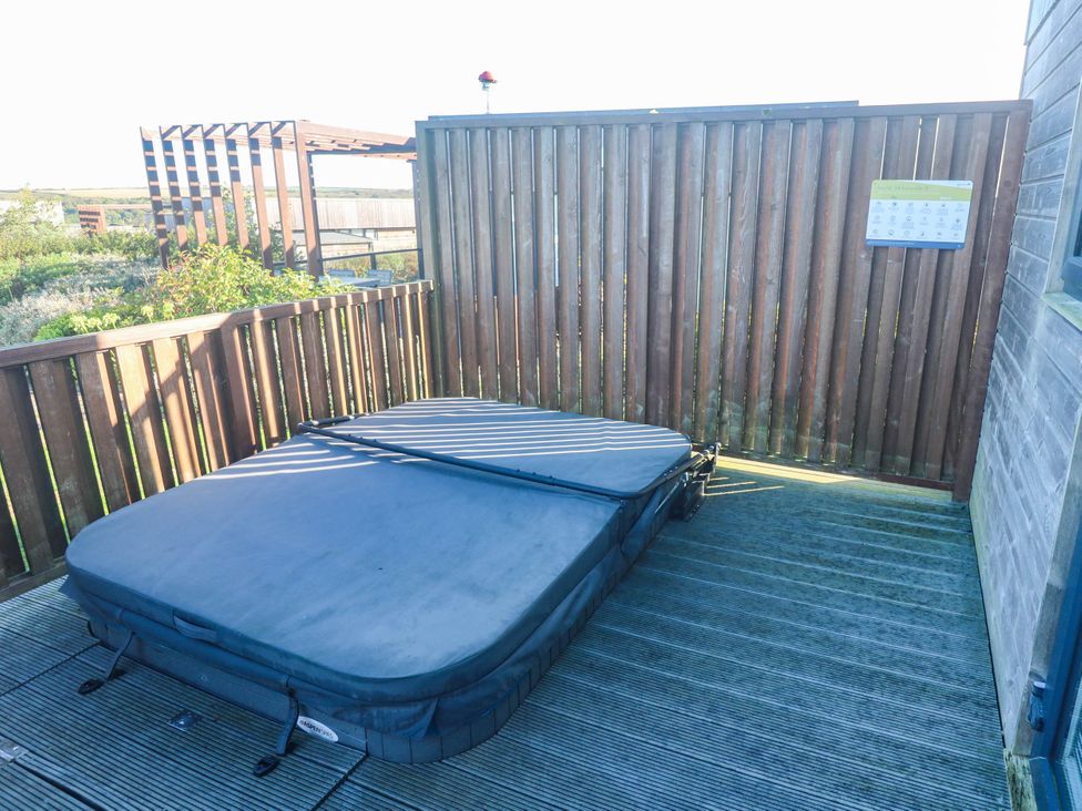 An outdoor area with a hot tub and wooden decking at 74 Porthmeor in Redruth