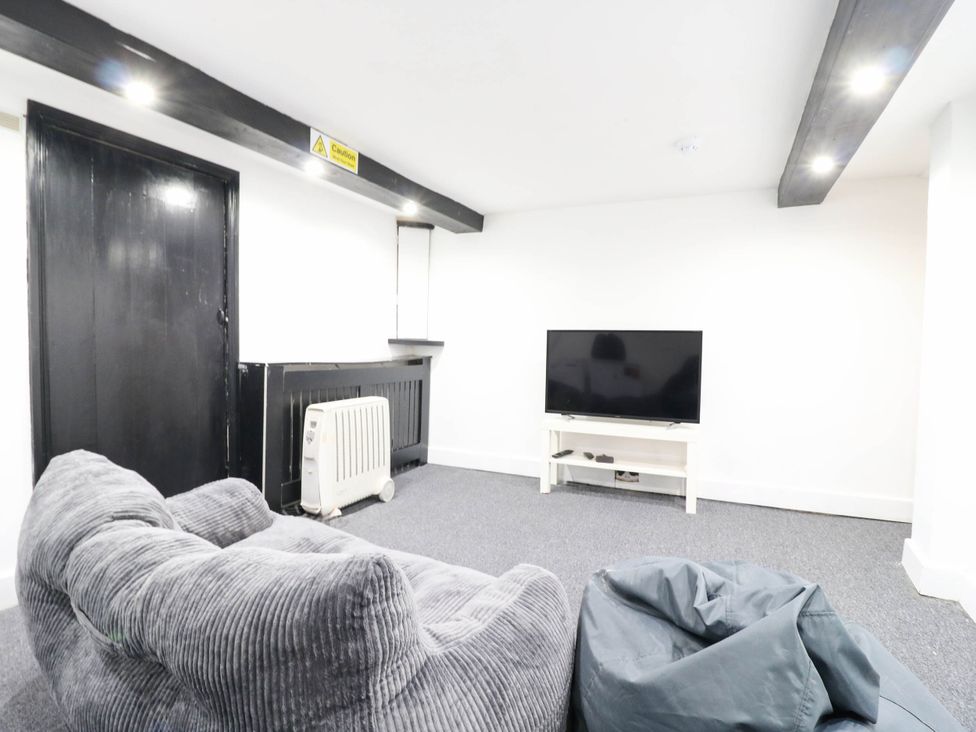 A living room with a black door and television setup at Gillingham House in Gillingham, Kent