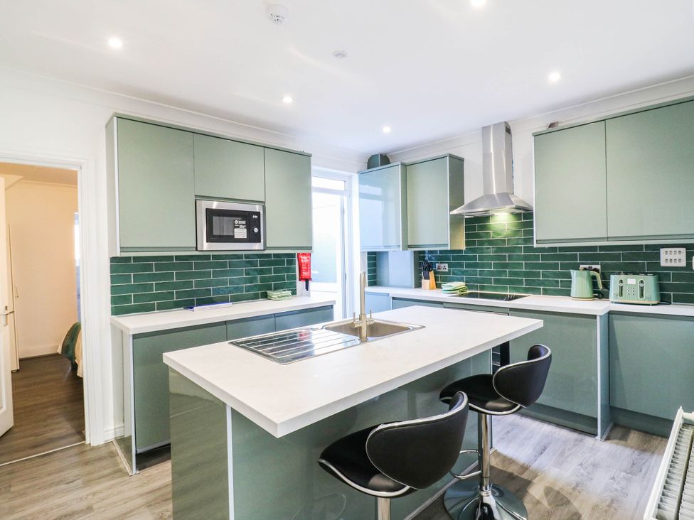 A kitchen with green cabinets and a microwave at Gillingham House in Gillingham, Kent