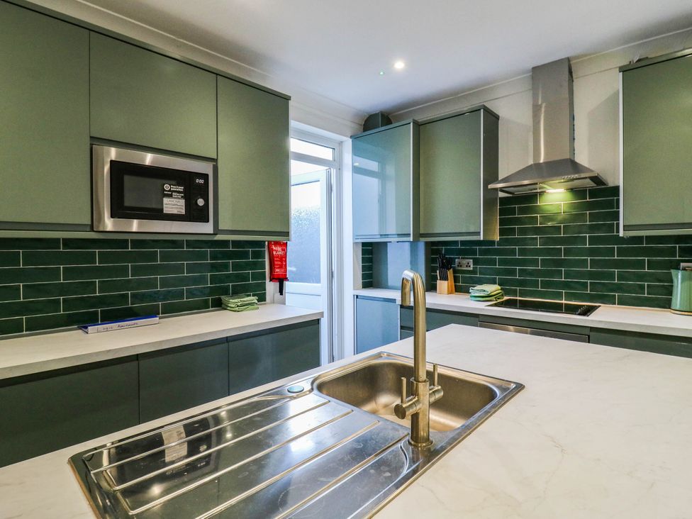 A kitchen with a sink and microwave at Gillingham House in Gillingham, Kent
