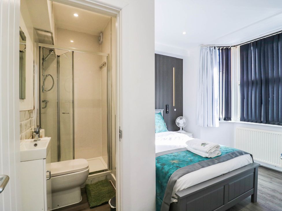 A bathroom with a shower and a bedroom with a bed at Gillingham House in Gillingham, Kent
