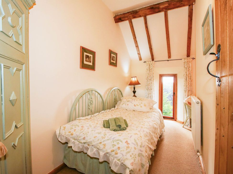 A bedroom with a bed, bedside lamp, and window at The Duck House at Hyssington Farm near Montgomery