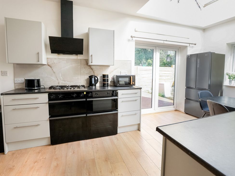 A kitchen with appliances and a door leading outside at 5 Woodland Crescent in Manchester