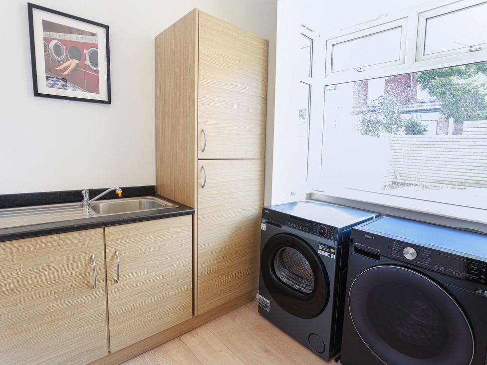 A laundry room with a sink and machines at 5 Woodland Crescent in Manchester