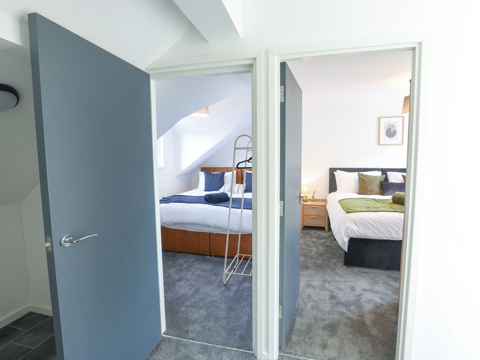 A bedroom with two beds and a clothes rack at 5 Woodland Crescent in Manchester
