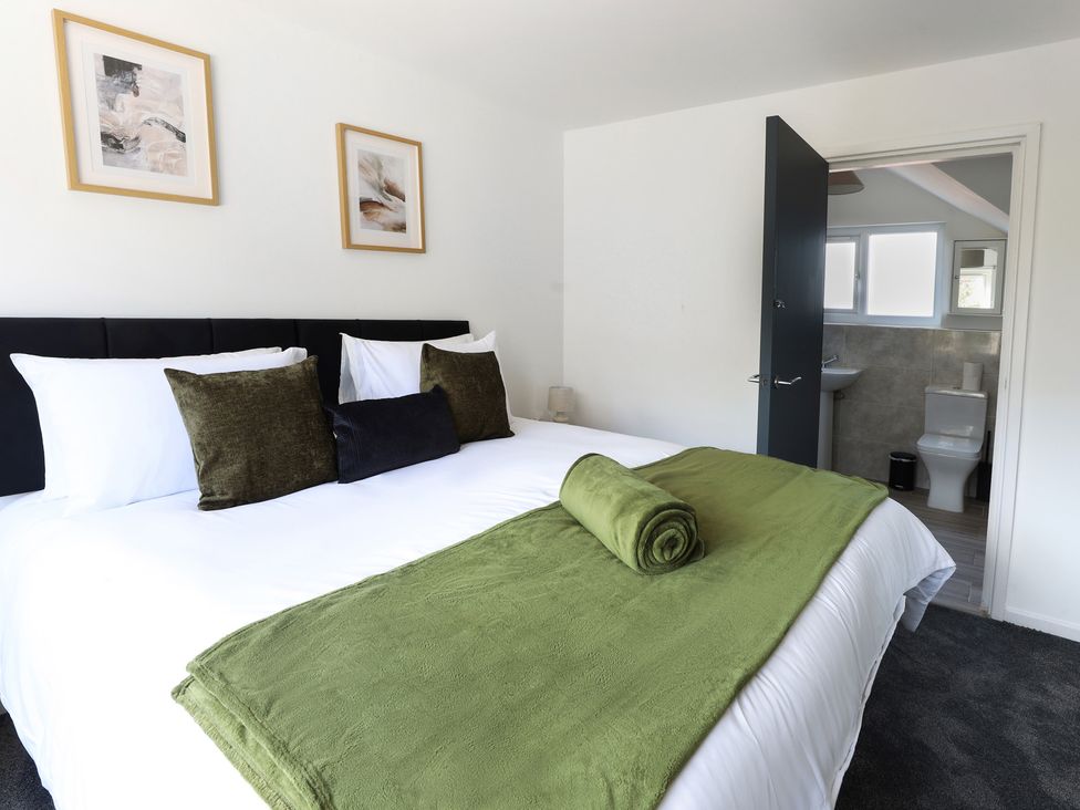 A bedroom with a bed and bathroom access at 5 Woodland Crescent in Manchester