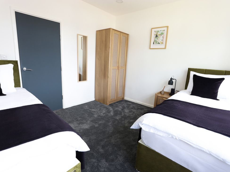 A bedroom with two beds and a wardrobe at 5 Woodland Crescent in Manchester