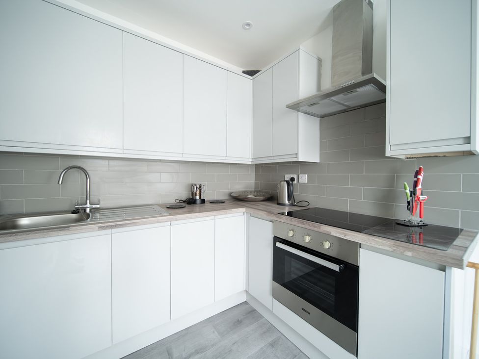 A kitchen with cabinets and appliances at Spacious Duplex Flat in Thornton-Cleveleys