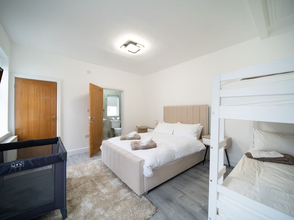 A bedroom with a double bed, bunk bed and a baby crib at Spacious Duplex Flat in Thornton-Cleveleys