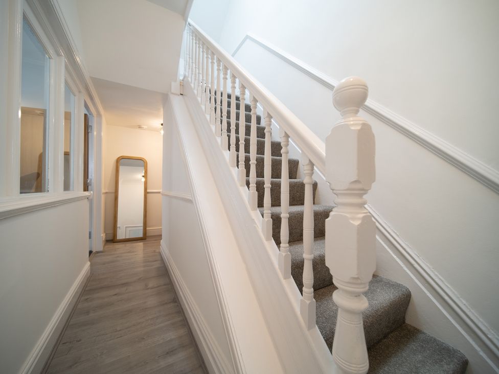 A hallway with a staircase and mirror at Spacious Duplex Flat in Thornton-Cleveleys