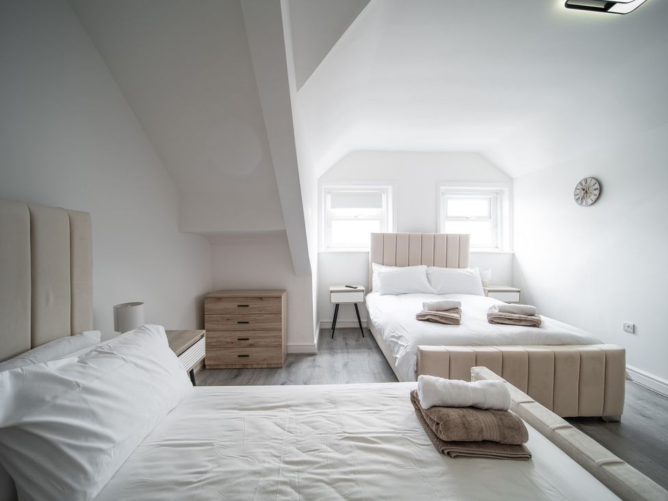 A bedroom with two beds and a nightstand at Spacious Duplex Flat in Thornton-Cleveleys