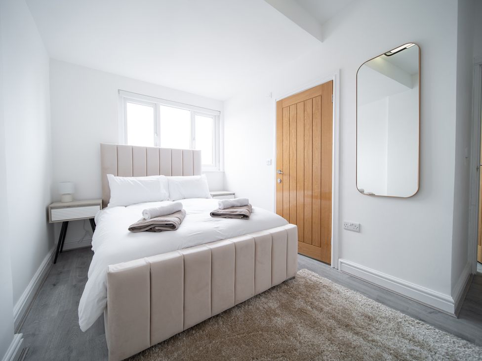 A bedroom with a bed and bedside table at Spacious Duplex Flat in Thornton-Cleveleys