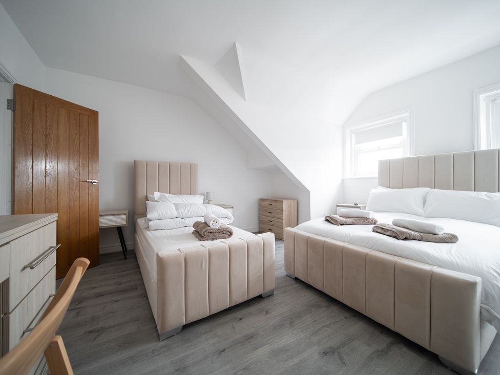A bedroom with two beds and a door at Spacious Duplex Flat Thornton-Cleveleys
