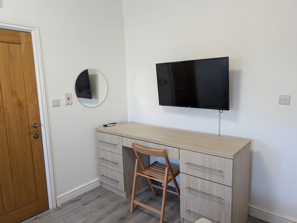 A desk and chair with a television on the wall at Spacious Duplex Flat in Thornton-Cleveleys