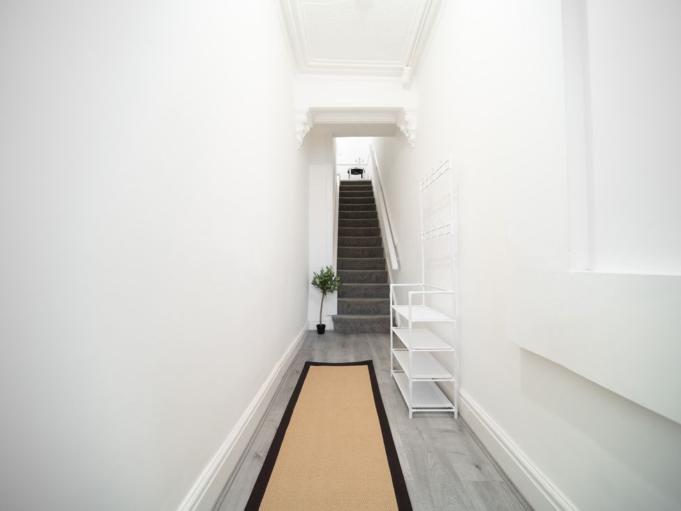 A hallway with a staircase and a small plant at Spacious Duplex Flat Thornton-Cleveleys