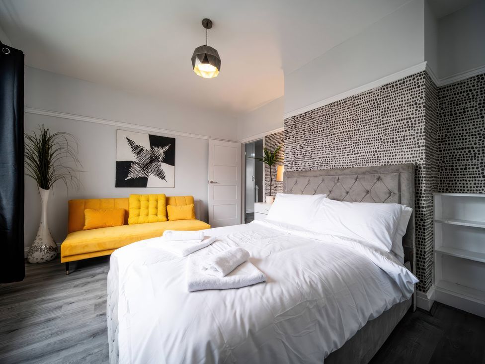 A bedroom with a bed and a yellow sofa at Flat with Terrace Style Rooftop in Thornton-Cleveleys