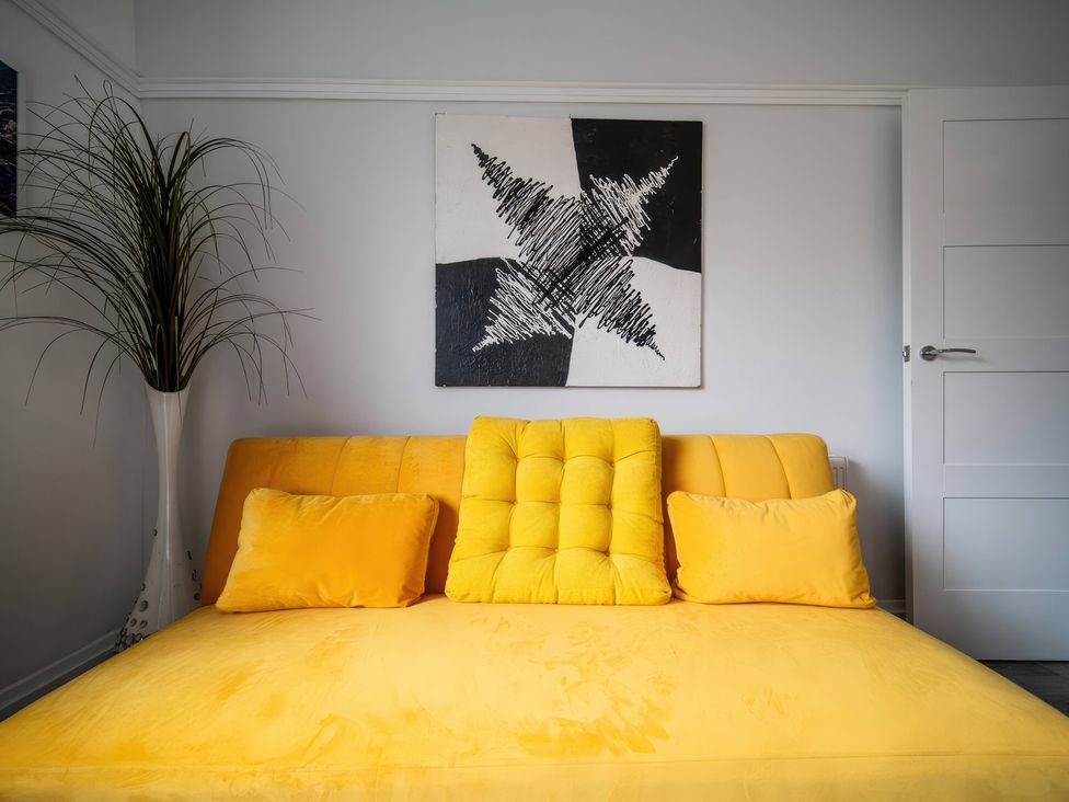 A living room with a yellow sofa and wall art at Flat with Terrace Style Rooftop Thornton-Cleveleys