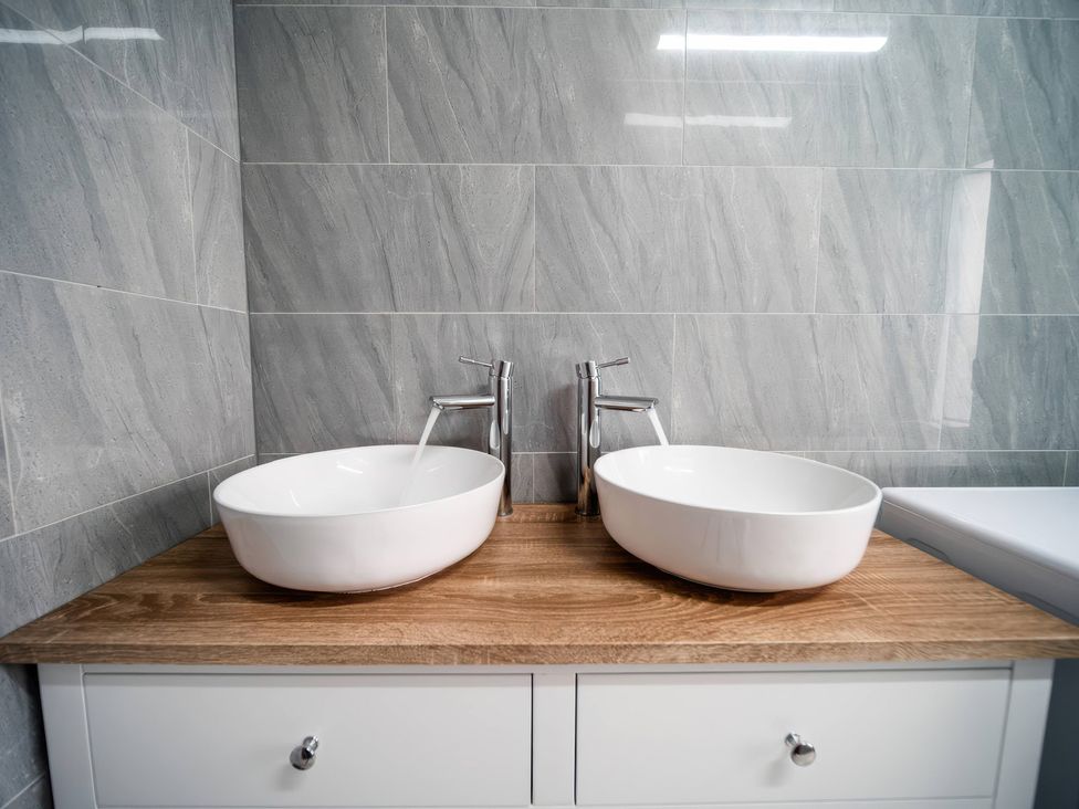 A bathroom with two basins and faucets on a wooden countertop at Flat with Terrace Style Rooftop in Thornton-Cleveleys