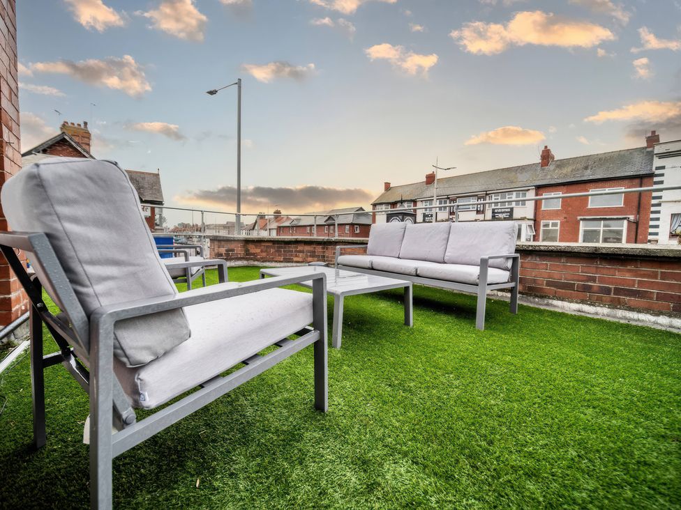 An outdoor terrace with seating and a table at Flat with Terrace Style Rooftop in Thornton-Cleveleys