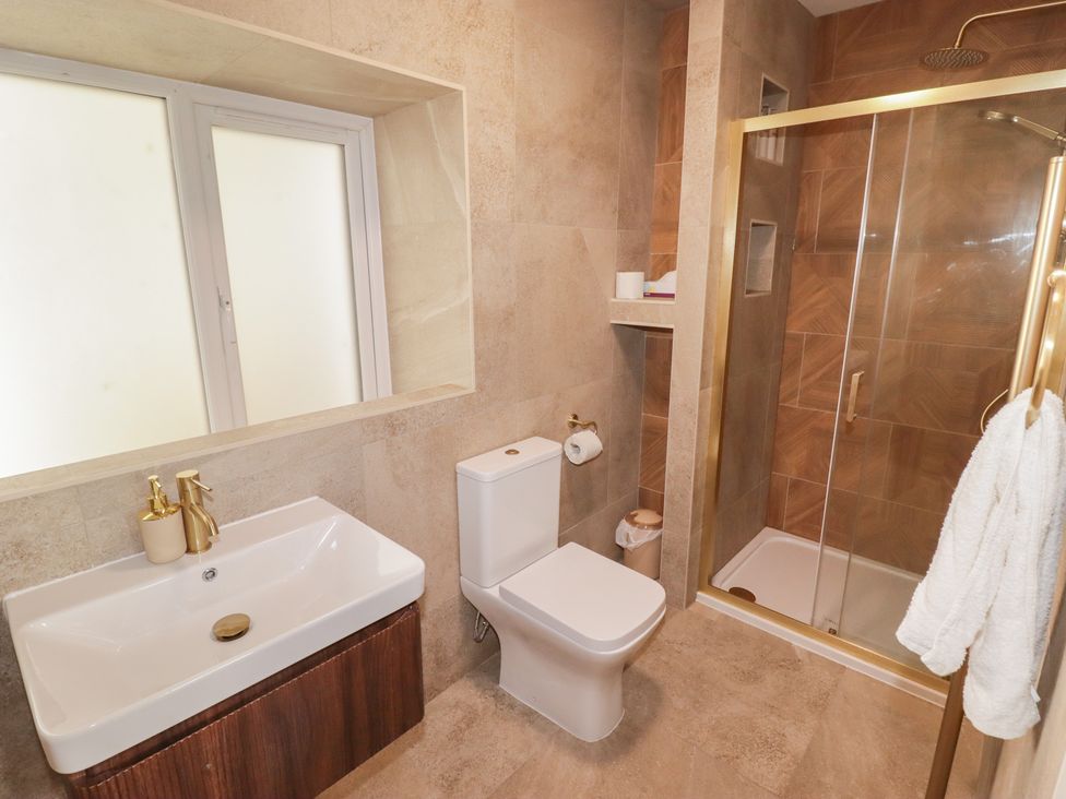 A bathroom with a sink, toilet, and shower at Flat 3 in Tenby