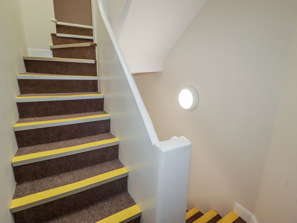 Stairs with a handrail and light fixture at Flat 3 in Tenby